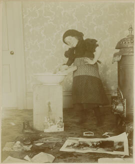 A young girl pretends to wash laundry with a washboard and basin