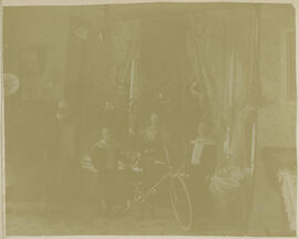 Carl, Edwin, and Harold Kaiser stand with a bicycle in the parlor