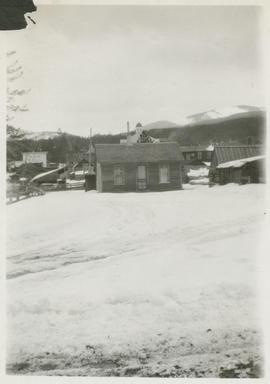 Snowy landscape and a small frame house with view of G.A.R Hall and Summit County Courthouse in B...