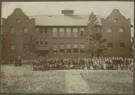 Group portrait of students and teachers outside the brick schoolhouse on Harris Street in Breckenridge