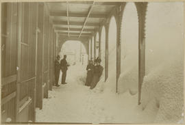 People under the portico of the Denver Hotel on snowy Main Street