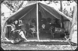 Kate Schwalbach sits at the entrance of a canvas platform tent