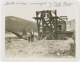 A couple pose by the Continental gold dredge on the Blue River