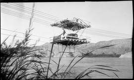 Cable tram ferry carries a man and an automobile across a wide river