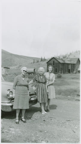 Three women pose by an automobile on Boreas Pass, east of Breckenridge